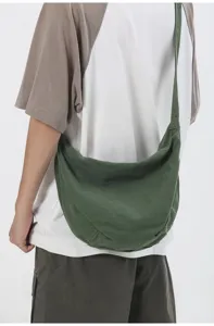 Vista detallada de un bolso cruzado de lona verde oscuro, diseño informal para uso diario.