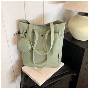 Sage green canvas tote bag detail, featuring dual handles, front pocket and round pouch.