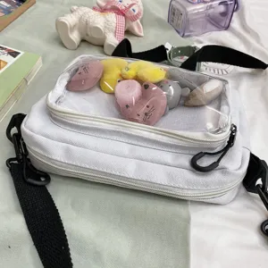 White canvas cross-body bag with clear front pocket and cute plush toys, stylish student bag.