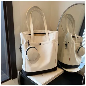 Detailed view of the chic white tote bag with black base, side pocket and mini coin pouch.