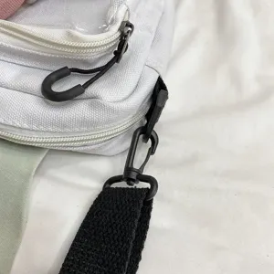 White canvas shoulder bag detail showing clear transparent window pocket and black hardware.