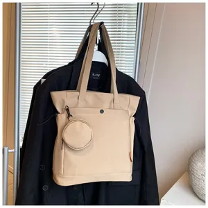 Detail view of a beige canvas tote bag featuring large capacity and an attached coin purse.