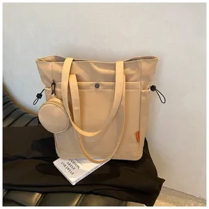Close-up view of beige tote bag showing dual handles, side drawstrings and mini pouch.