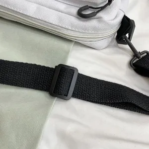 Close-up detail showing white canvas shoulder bag strap, black adjustable plastic buckle & zipper.