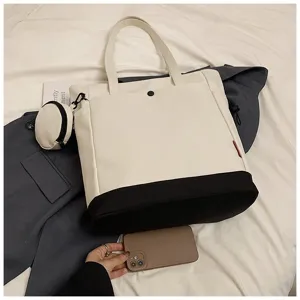 Close-up detail of the large two-tone tote bag with a small coin purse and sturdy shoulder strap.