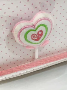 Dettaglio ravvicinato di zaino rosa a pois con cuore di lecca-lecca ricamato in peluche.