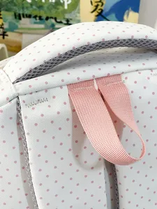 Vista dettagliata ravvicinata della cinghia dello zaino a pois rosa e della maniglia.