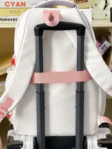 Primo piano dettaglio dello zaino scolastico a pois rosa con pratica cinghia per valigia.
