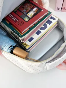 Primo piano della capacità interna di un simpatico zaino a pois rosa pieno di libri.