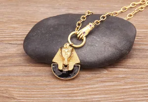 Nahaufnahme des goldenen ägyptischen Pharao-Anhängers auf dunklem Naturstein-Hintergrund.