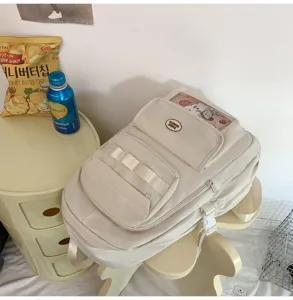 Vista dettagliata del grande zaino scolastico beige con finestra trasparente e tasche multiple.