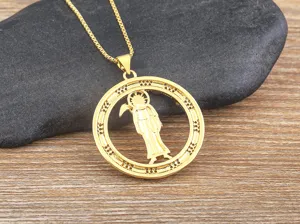 Close-up detail of vintage 18k gold plated grim reaper scythe pendant with sparkling cubic zirconia.