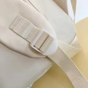 Primo piano dettagliato della robusta cinghia per zaino beige con fibbia in plastica.