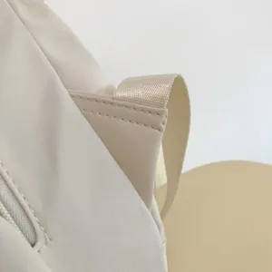 Vista dettagliata dello spallino dello zaino e della cucitura curata in morbido beige.