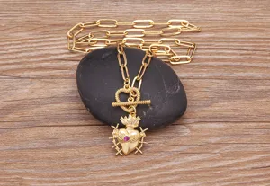 Primo piano dettagliato di una collana punk dorata con ciondolo a cuore e spessa catena.
