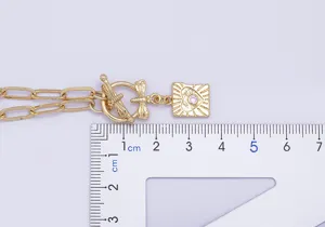 Dettaglio collana punk placcata oro con chiusura a libellula e ciondolo quadrato con cristallo.