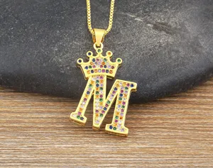 Detailed close-up view of a gold-colored crown letter M pendant necklace with colorful cubic zirconia.
