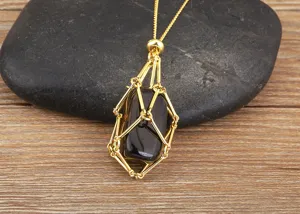 Close-up detail of the 18K gold plated metal cage necklace pendant with a black natural crystal.