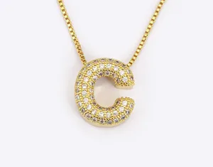 Close-up of a gold-plated letter C pendant necklace with pave cubic zirconia stones.
