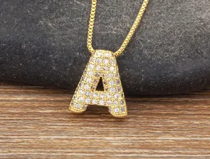 Closeup detail of a gold micro pave cubic zirconia letter A pendant necklace on stone background.