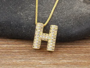 Detail shot of gold letter H pendant necklace with micro-pave cubic zirconia on wooden background.