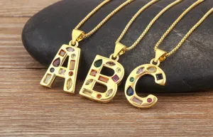 Close-up detail of gold-plated alphabet letter pendants inlaid with colorful cubic zirconia stones.