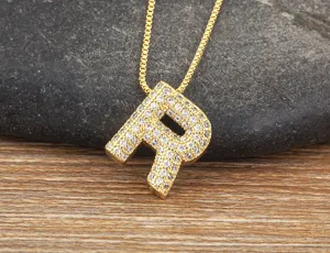 Close-up detail of the gold letter R pendant necklace sparkling with micro-set cubic zirconia.