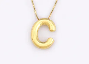 Close-up detail of the glossy gold bubble letter C pendant hanging on a delicate chain.