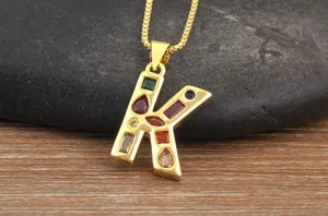 Detail view of gold-plated letter K pendant necklace with colorful cubic zirconia stones.
