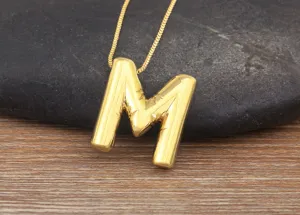 Gold-plated puff letter M pendant necklace detail view showcasing smooth metallic texture.