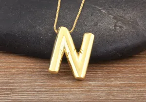 Gold plated letter N pendant necklace detail, featuring a stylish shiny bubble alphabet design.