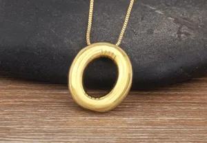 Detailed close-up of gold-plated 3D bubble letter O pendant necklace on textured surface.