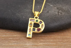 Gold plated letter P pendant detail, colorful cubic zirconia inlay, elegant jewelry close up.