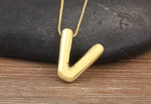 Gold puffed letter V pendant necklace close up, smooth metal surface detail shot.