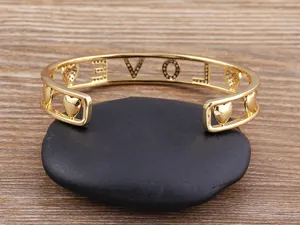 Vergoldeter offener Armreif mit hohlen LOVE Buchstaben und süßen Herz-Charms für Damen.