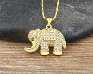 Vista detallada de colgante de elefante bañado en oro con cristales microengastados brillantes en madera.