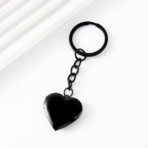 Gros plan détaillé du porte-clés médaillon cœur noir, pendentif photo en métal brillant.