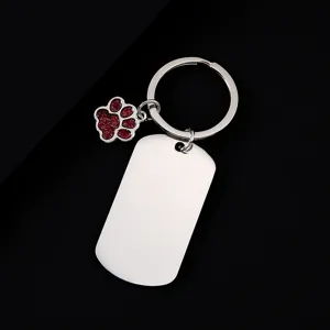 Close-up detail of stainless steel dog tag keychain with red glitter paw pendant accessory.