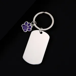 Stainless steel military dog tag keychain with cute purple glitter paw pendant, detail view.