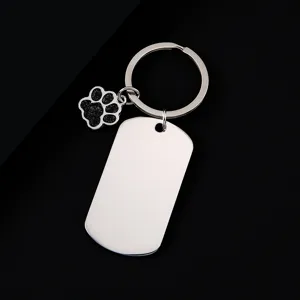 Close-up of stainless steel military dog tag and cute paw print keychain pendant.