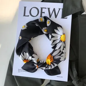 Detailansicht des eleganten schwarzen Seidentuchs mit feinem weißen Gänseblümchen-Muster.