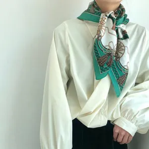 Vintage green silk scarf detail showcasing classic chain and carriage print design.