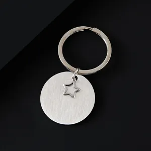Gros plan détail du porte-clés rond en acier inoxydable brossé avec anneau et pendentif étoile.
