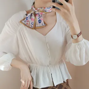 Primer plano detallado del pañuelo de seda estrecho con estampado floral elegante al cuello.