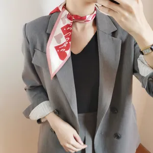 Dettaglio di un elegante foulard in seta con stampa a cuore rosso e bianco al collo.