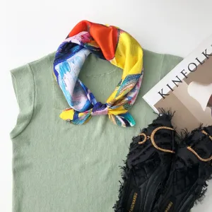Vista dettagliata di un foulard in seta colorata con motivo astratto su top in maglia.