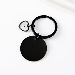 Detailed view of the black stainless steel keychain featuring a round disc and heart seed pendant.