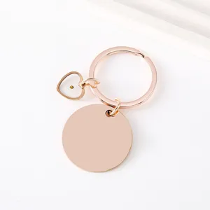 Detail view of rose gold mustard seed keychain with blank round tag and heart pendant.