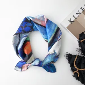 Dettaglio di un foulard in seta con stampa artistica ad olio in tonalità blu e arancione.