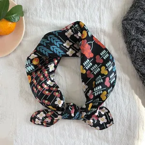 Nahaufnahme eines stilvollen schwarzen Seidentuchs mit Blumenmuster für elegante Damenlooks.
